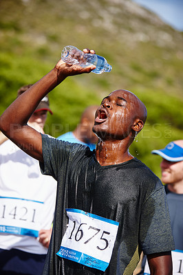 Buy stock photo Shot of a young male runner pouring water over himself after a road race