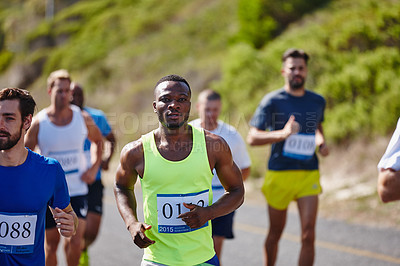 Buy stock photo Shot of a group of young men running a marathon