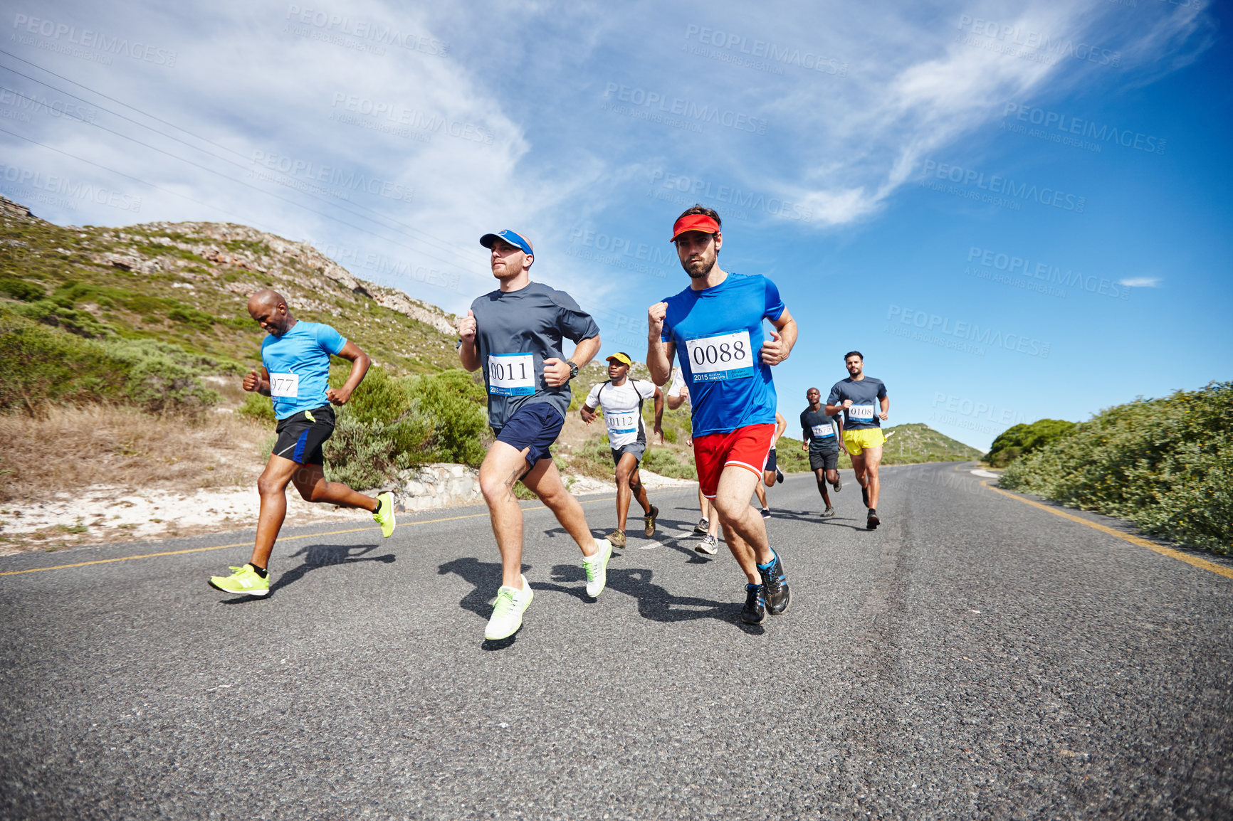 Buy stock photo Shot of a group of young men running a marathon