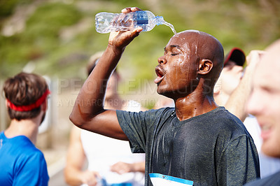 Buy stock photo Shot of a young male runner pouring water over himself after a road race