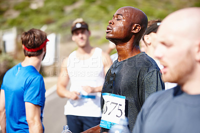 Buy stock photo Shot of a group of young runners catching their breath and drinking water after a race