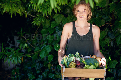 Buy stock photo A young woman holding a crate of vegetables outdoors