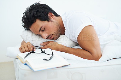 Buy stock photo Sleeping, reading and a young man in the bedroom of his home with a book to relax or rest on the weekend. Study, learning or education with a tired person asleep on a book while lying in bed