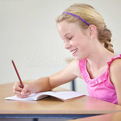 Buy stock photo Kid, school and smile for writing in classroom, studying lesson or learning knowledge at desk. Child, student or happy girl drawing in notebook of academic development, educational test or assessment