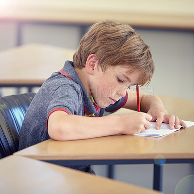 Buy stock photo Child, student and writing in classroom for learning, education and development in language quiz or test. Smart boy or kid with notebook for school progress, creativity and knowledge at his desk