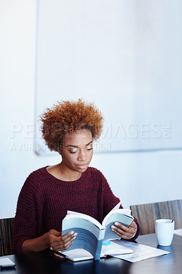 Buy stock photo Shot of an attractive young woman reading a book in the office