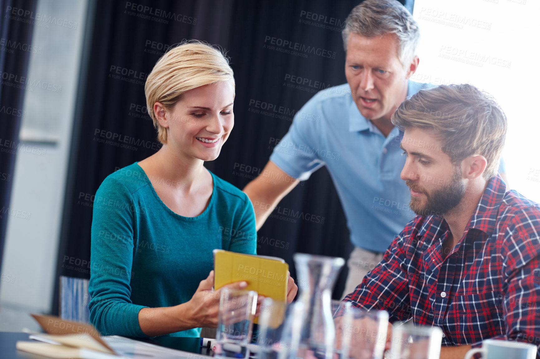 Buy stock photo Shot of a group of colleagues having a discussion over a digital tablet