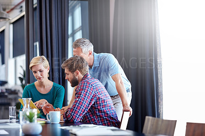 Buy stock photo Shot of a group of colleagues having a discussion over a digital tablet