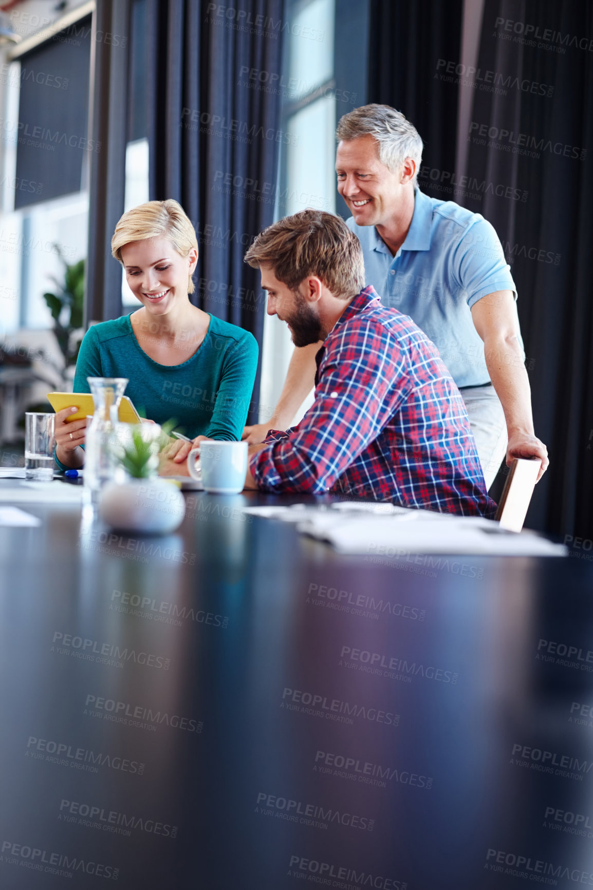 Buy stock photo Shot of a group of colleagues having a discussion over a digital tablet