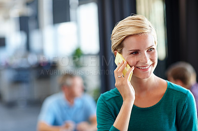 Buy stock photo Shot of an attractive woman using her cellphone with her colleagues blurred in the background