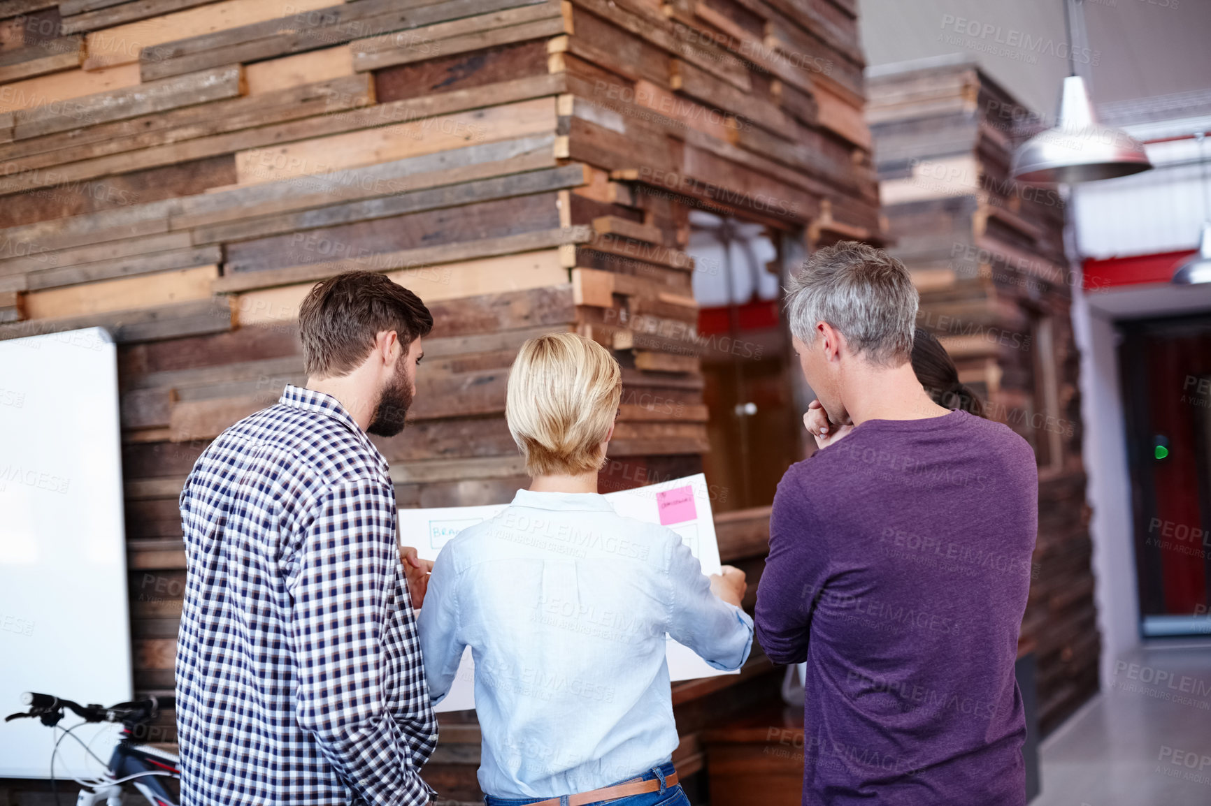 Buy stock photo A group of colleagues looking over some plans