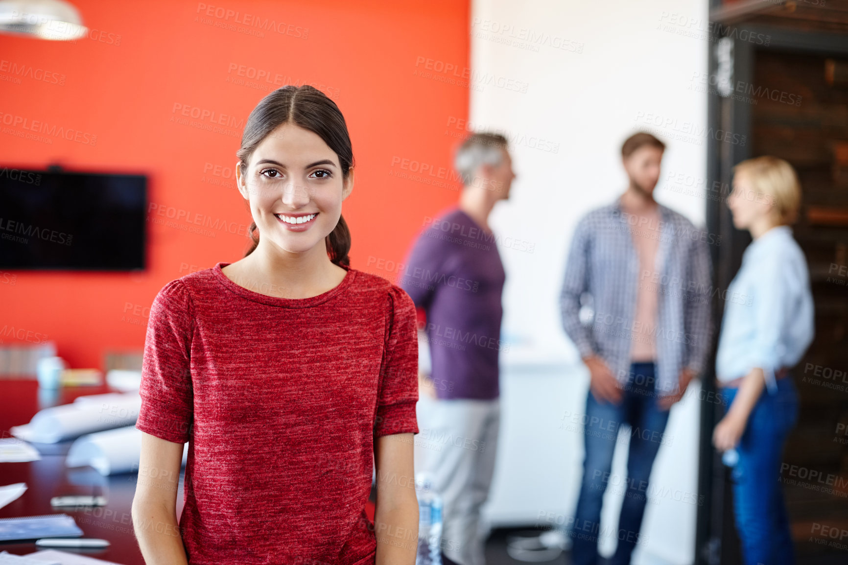 Buy stock photo Portrait of a young designer with her colleagues standing in the background