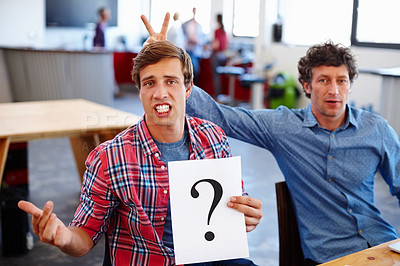 Buy stock photo Portrait of two coworkers looking confused while holding a question mark sign