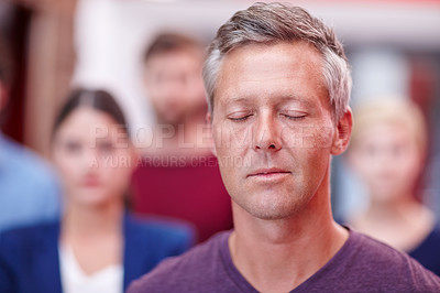 Buy stock photo Shot of an office worker standing with his eyes closed with coworkers in the background