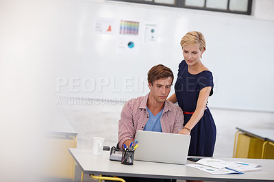 Buy stock photo Cropped shot of two young colleagues working on a laptop
