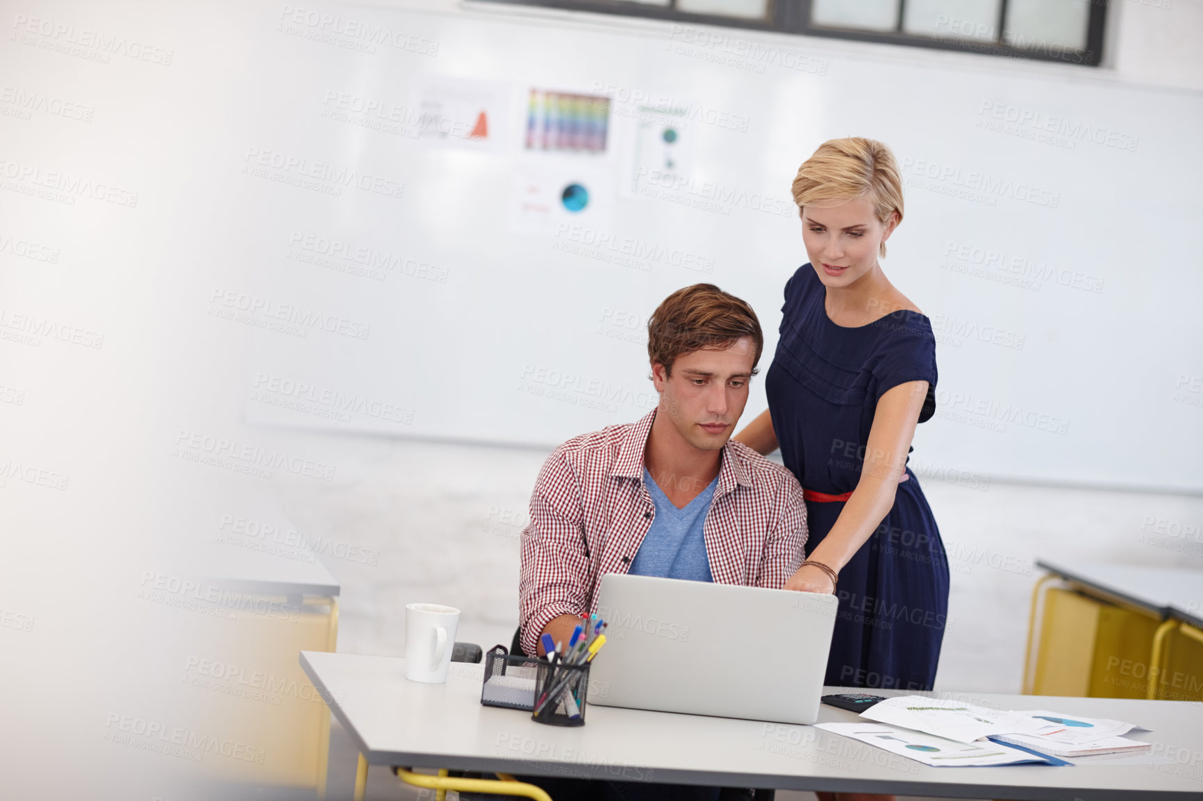 Buy stock photo Cropped shot of two young colleagues working on a laptop