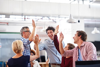 Buy stock photo A group of designers high-fiving each other during an informal office meeting