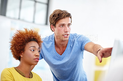 Buy stock photo Cropped shot of two young colleagues working on a pc
