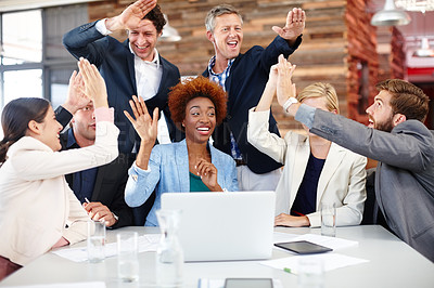 Buy stock photo A group of designers celebrating good news while working together at a laptop