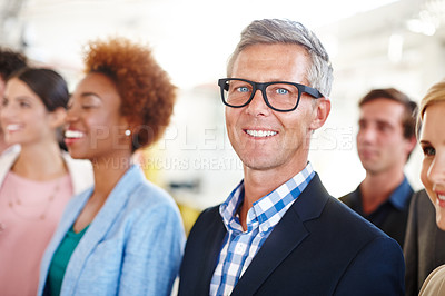 Buy stock photo Cropped portrait of a mature businessman standing amongst his colleagues in the office