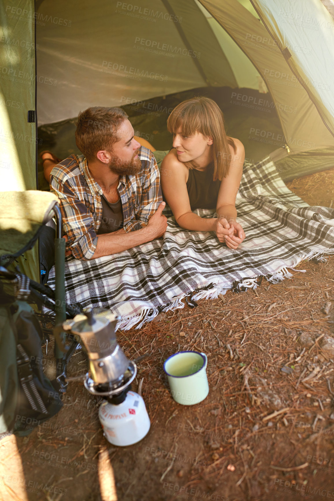 Buy stock photo Shot of a young couple lying in a tent looking outwards