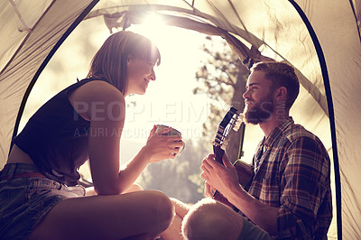 Buy stock photo Shot of a young man playing guitar to his girlfriend in a tent