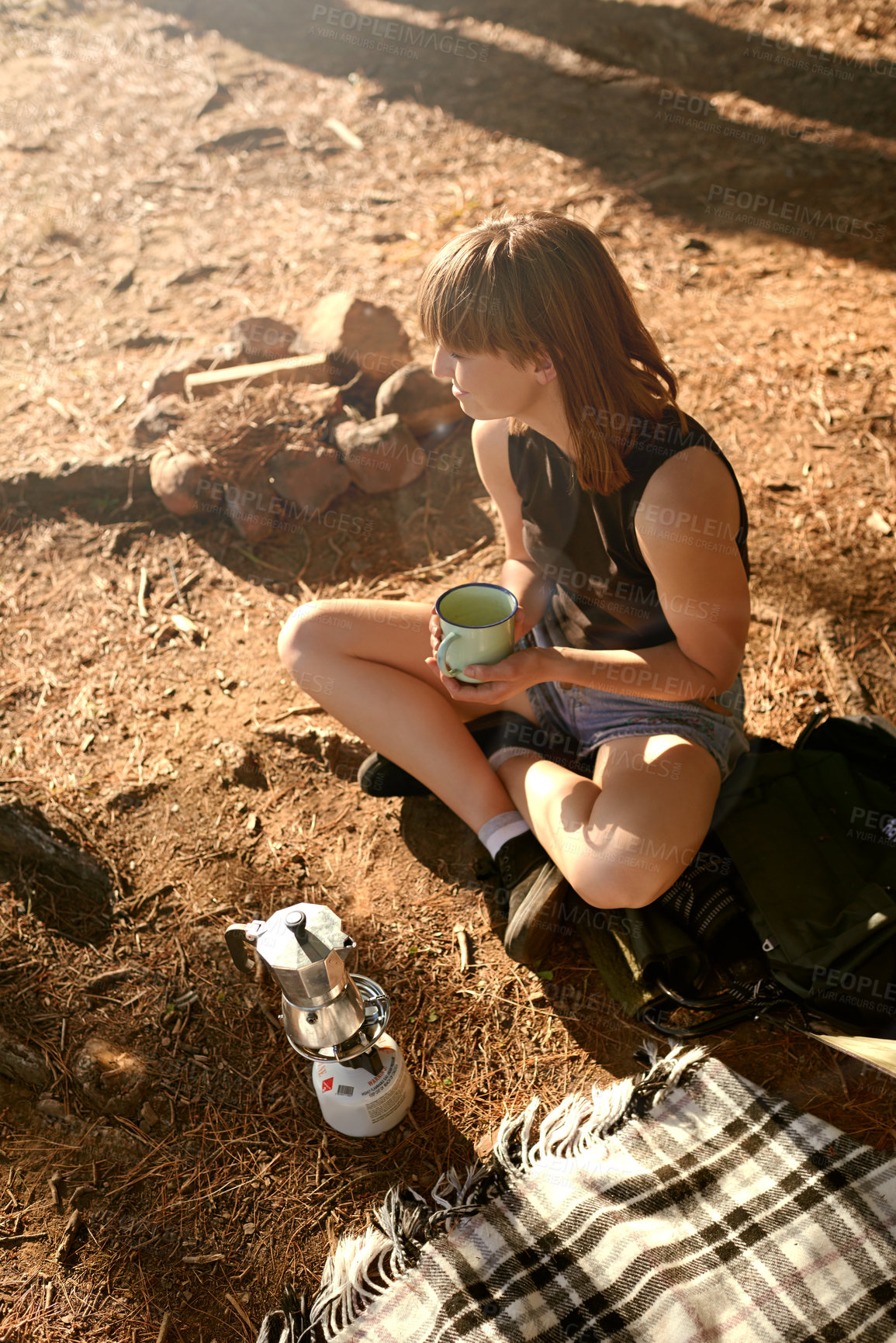 Buy stock photo Shot of a young woman drinking coffee while camping