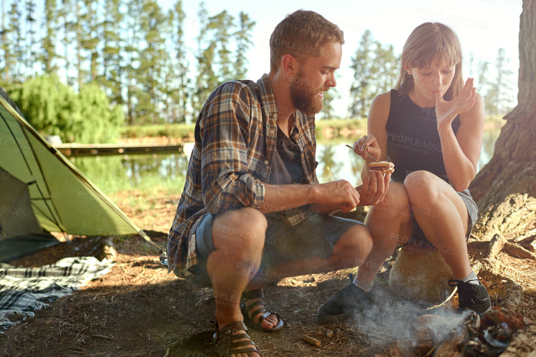 Buy stock photo Shot of a young couple making smores while camping