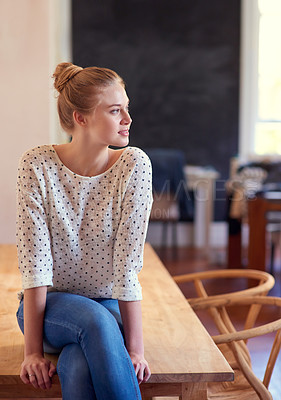 Buy stock photo Shot of a young woman sitting on the kitchen table