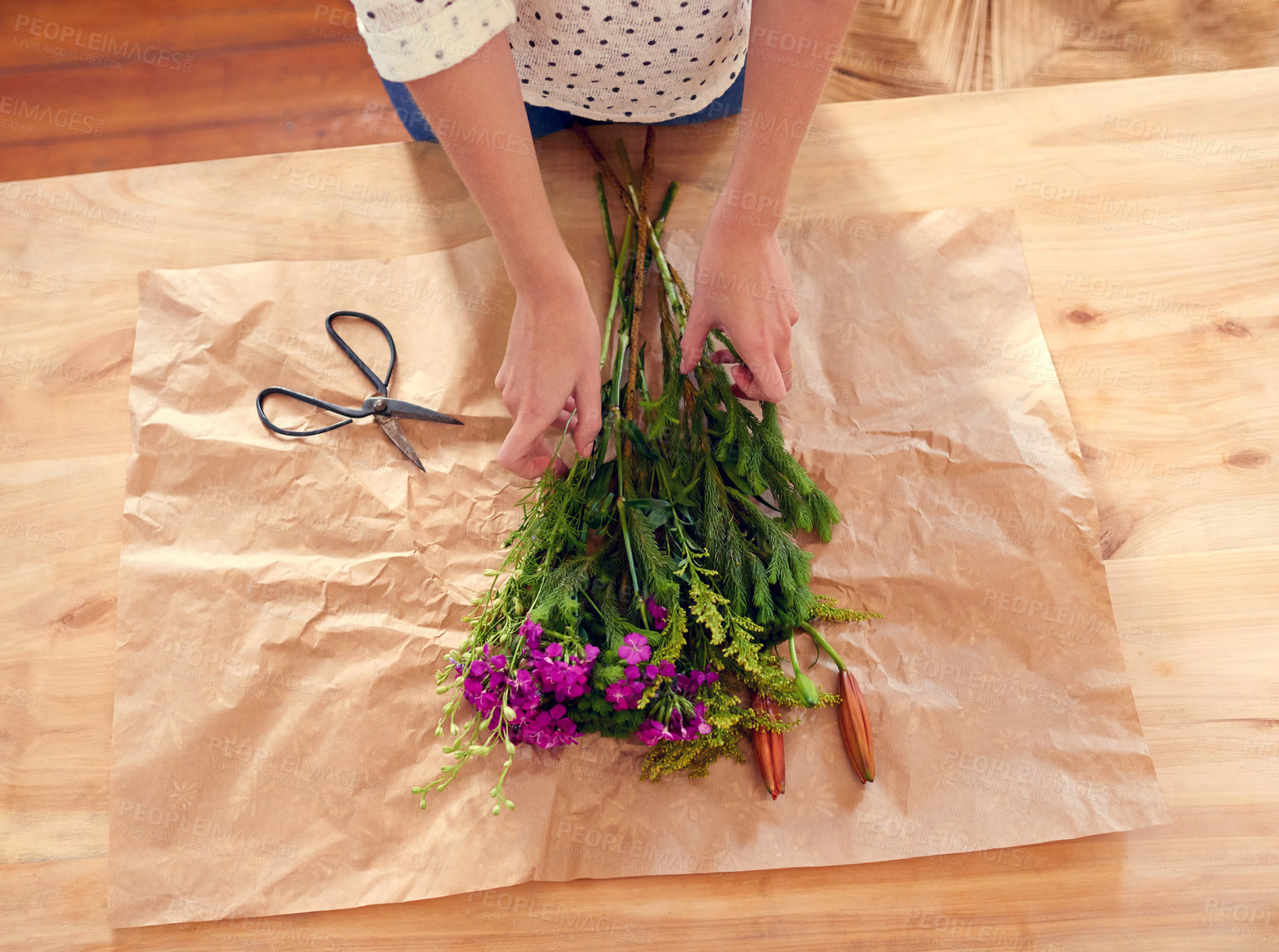 Buy stock photo Cropped shot of a young woman arranging flowers at home