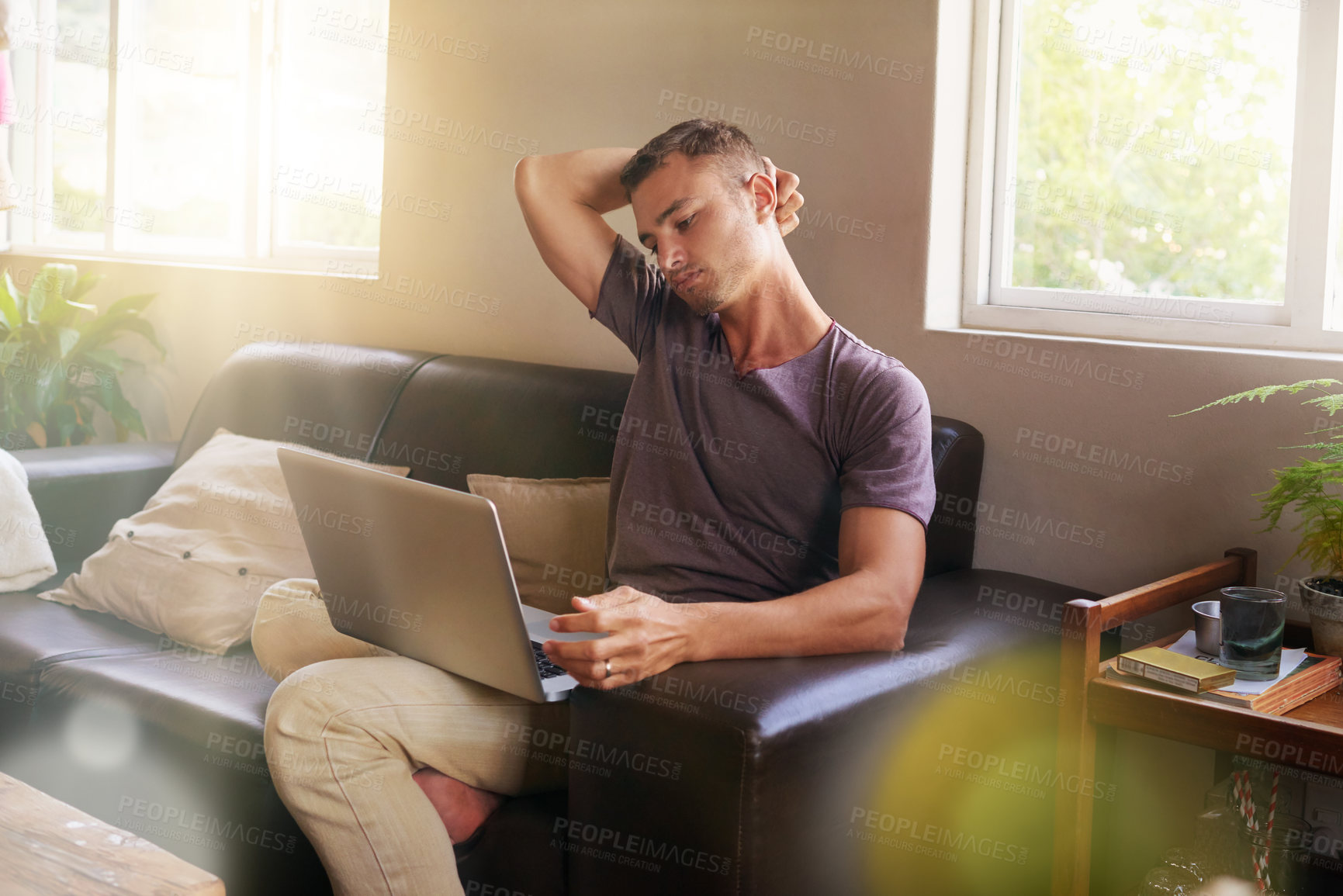 Buy stock photo Shot of a handsome young man using a laptop on the sofa at home
