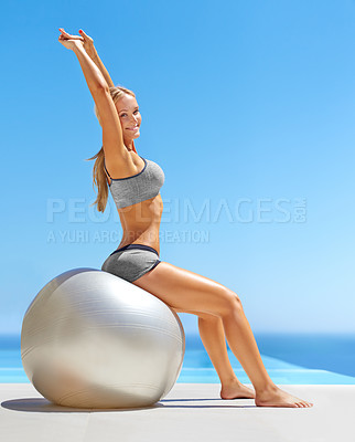Buy stock photo Shot of an attractive young woman working out with an exercise ball by a swimming pool
