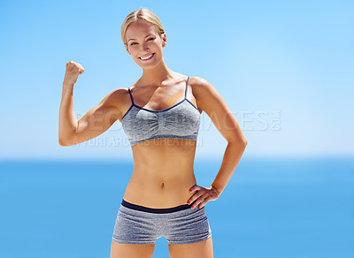 Buy stock photo Portrait of an attractive young woman in exercise clothing flexing her bicep outside