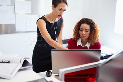Buy stock photo Shot of two attractive designers at work on a computer in the office