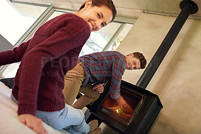 Buy stock photo Shot of a young couple preparing their fireplace at home