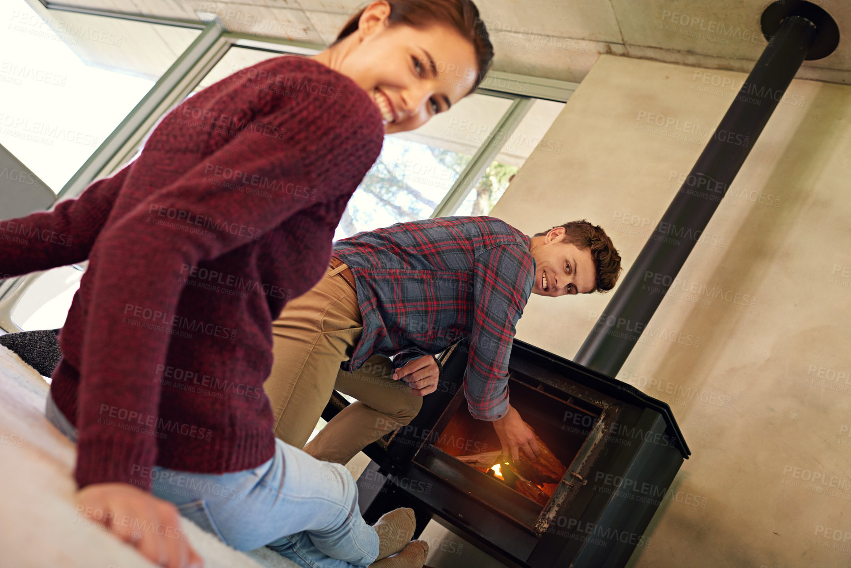 Buy stock photo Shot of a young couple preparing their fireplace at home