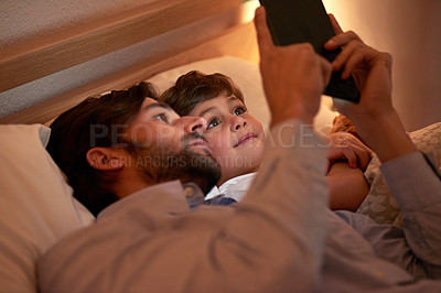 Buy stock photo Shot of a father and son using a digital tablet together while lying in bed