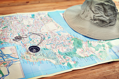 Buy stock photo Hat, map and travel guide with compass on table for itinerary schedule, adventure explore and direction. Vintage, geography and location with holiday planning for tourism, navigation and discovery