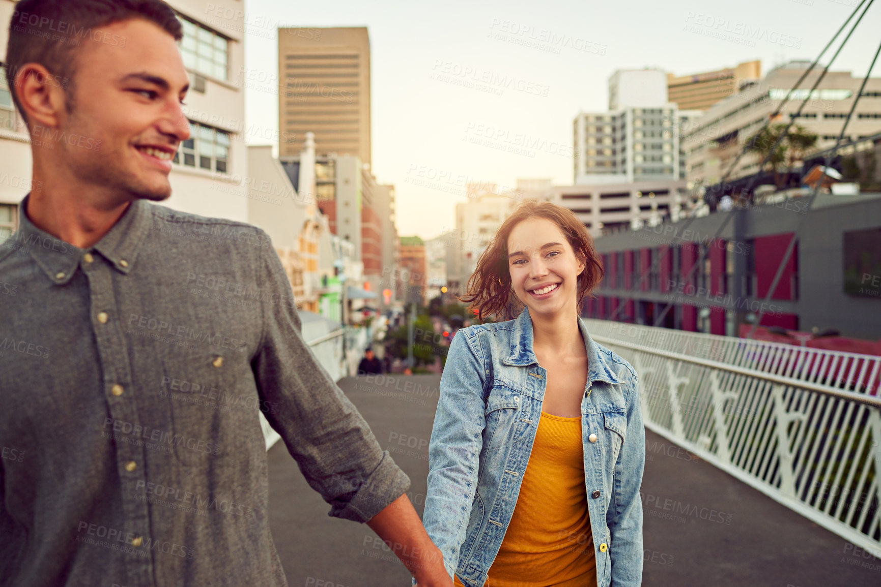 Buy stock photo Shot of a happy young couple enjoying a romantic walk together in the city