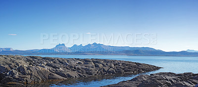 Buy stock photo Landscape of a river between rocks with blue sky copy space. Rocky shore of a clear water riverbank in Norway. Calm stream near a picturesque wilderness against bright horizon. Peaceful nature scene