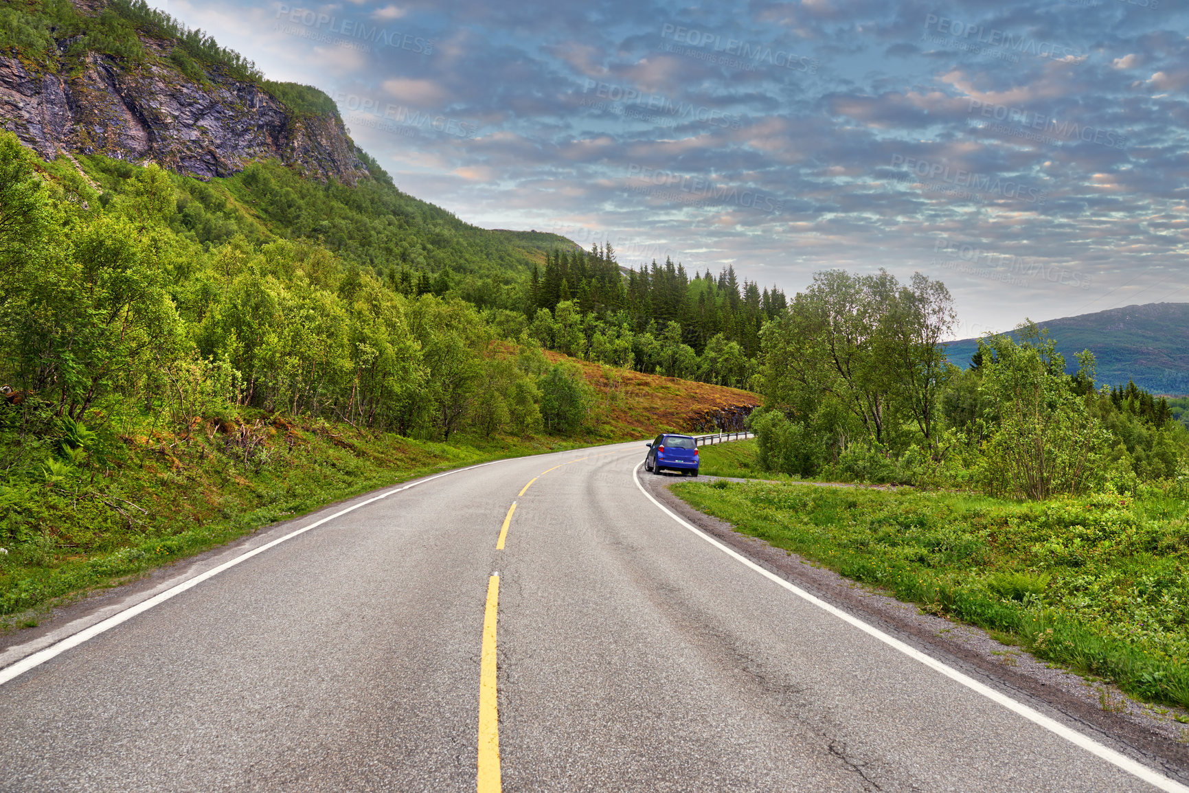 Buy stock photo Outdoor, road and car in forest by mountains, fjord and trees for transport system in summer. Landscape, clouds and traffic with highway, infrastructure and travel in environment by street in Norway