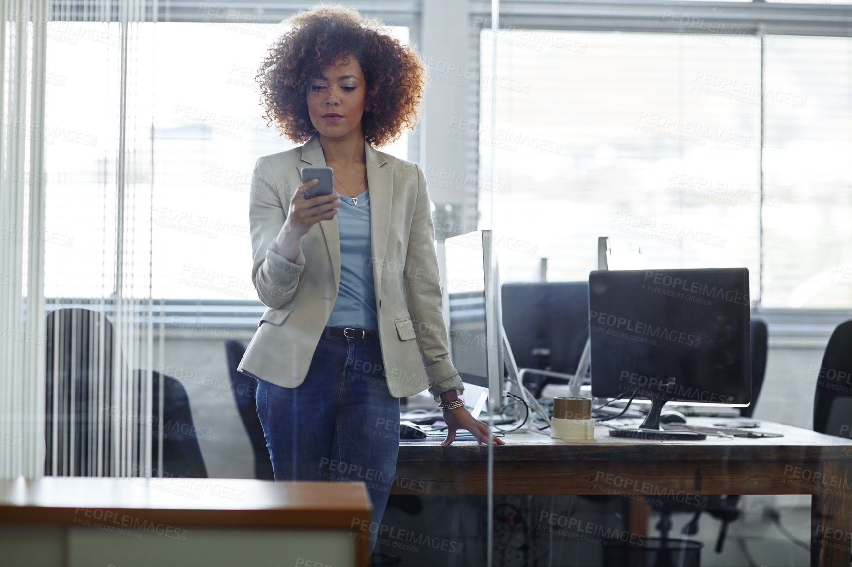 Buy stock photo Cropped shot of a beautiful young businesswoman using her phone in the office