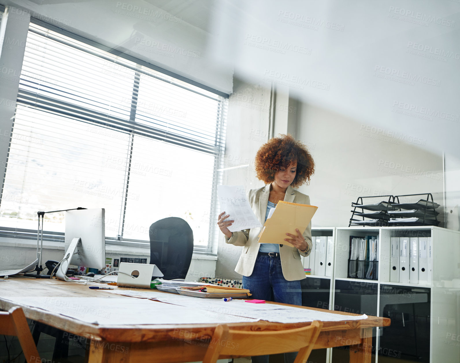 Buy stock photo Cropped shot of a beautiful young businesswoman looking over some documents in her office