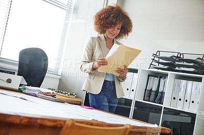 Buy stock photo Cropped shot of a beautiful young businesswoman looking over some documents in her office