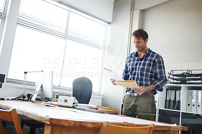 Buy stock photo Cropped shot of a handsome businessman looking over some documents in his office