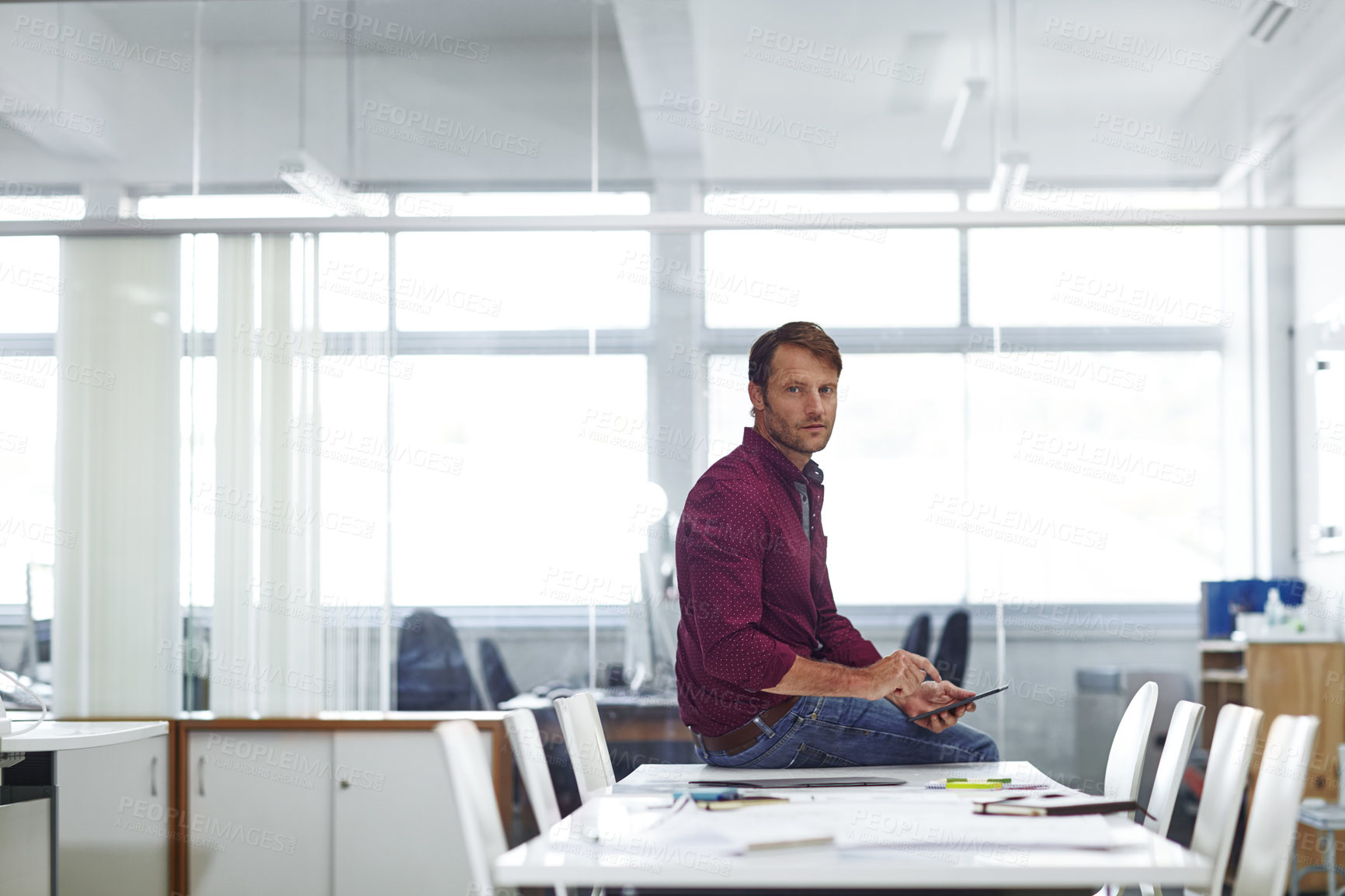 Buy stock photo Cropped shot of a handsome businessman using his tablet in the office