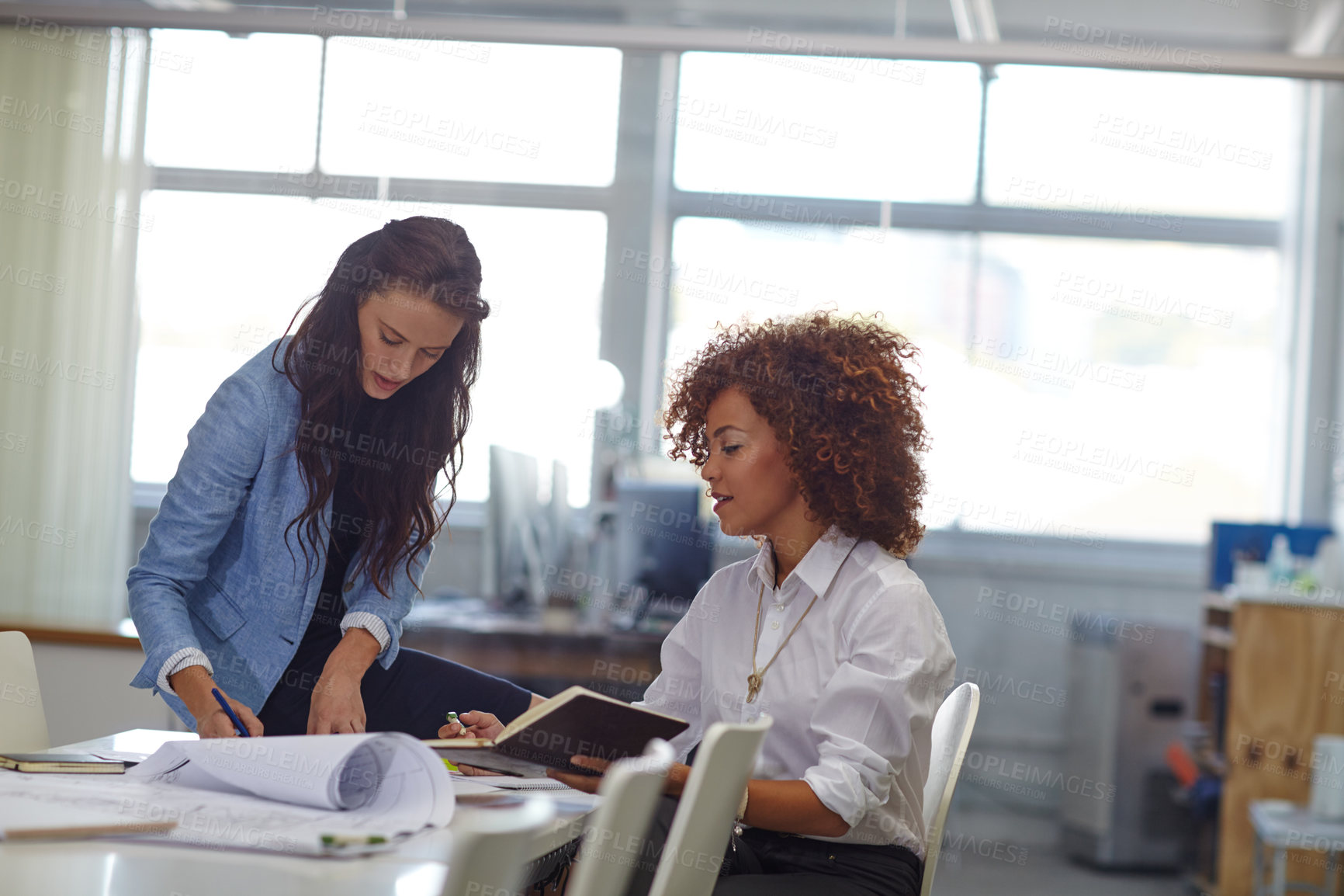 Buy stock photo Shot of two young female designers discussing work in the office