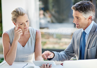 Buy stock photo Shot of two mature businesspeople talking together of a digital tablet