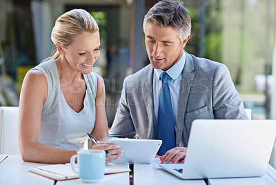 Buy stock photo Shot of two mature businesspeople talking together of a tablet and laptop