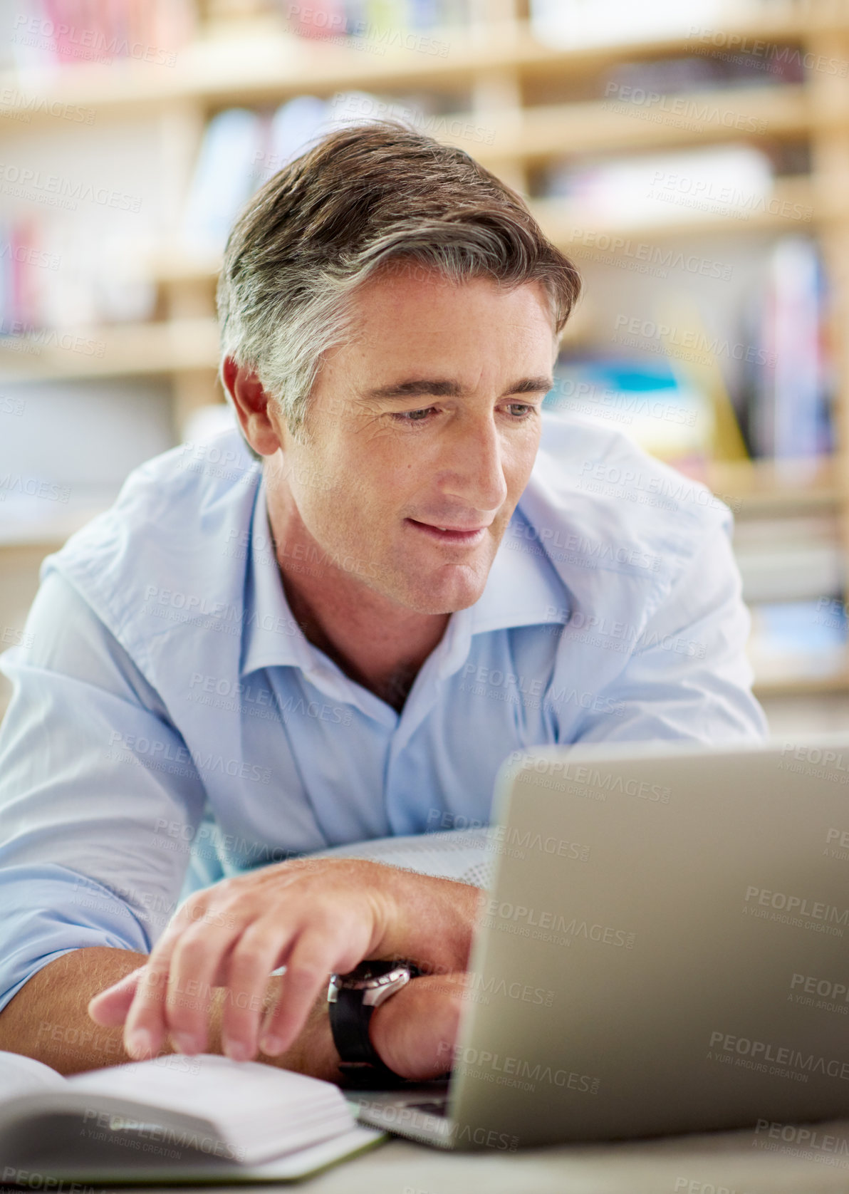 Buy stock photo Shot of a handsome mature man lying on his living room floor using a laptop